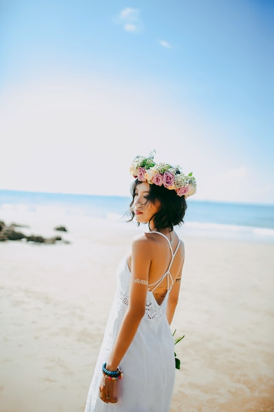 白天摄影时，穿着白色意大利面束带连衣裙的女子站在海边